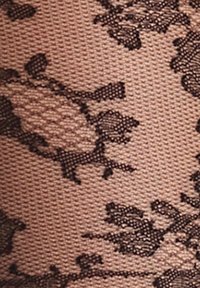 Primo piano di un tessuto beige con sovrapposizione di pizzo floreale nero che crea un motivo dettagliato e texturizzato.