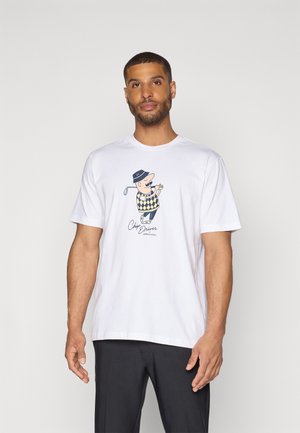 Hvid bomulds t-shirt med en grafik af en mand i golfudstyr, iført en harlequin-mønstret sweater og en hat, trykt nedenfor illustrationer.