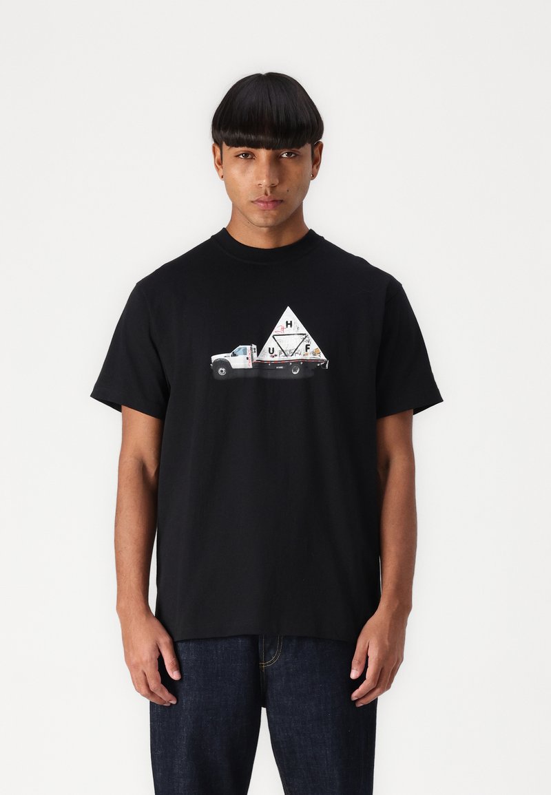 Sort bomulds t-shirt med et grafisk print af en hvid lastbil og et trekantet design med teksten "HUF" i midten. Enkel crew neck design.