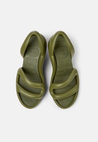 Green rubber sandals with a wavy design and textured sole. Features thick straps and an ergonomic shape for comfort.