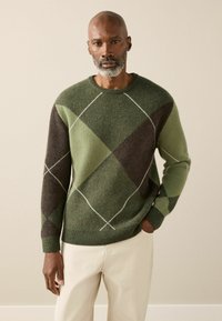 Green and brown argyle knit sweater with a ribbed neckline and cuffs, featuring white diagonal stitching across the diamond pattern.