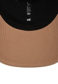 Cappello con una visiera in tessuto beige e parte inferiore nera. Presenta una superficie testurizzata, cuciture a vista e etichetta "9FORTY" all'interno.