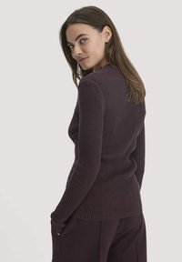 Gestreifter, dunkelvioletter Langarmpullover mit taillierter Passform. Die strukturierte Stoffqualität, der runde Ausschnitt und die schmale Silhouette unterstreichen seine Form.