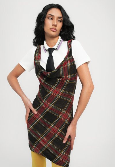 Schwarzes karriertes Kleid mit roten und gelben Akzenten, das über einen Schalkragen verfügt. Kombiniert mit einem weißen Poloshirt und einer schwarzen Krawatte, vor einem neutralen Hintergrund.