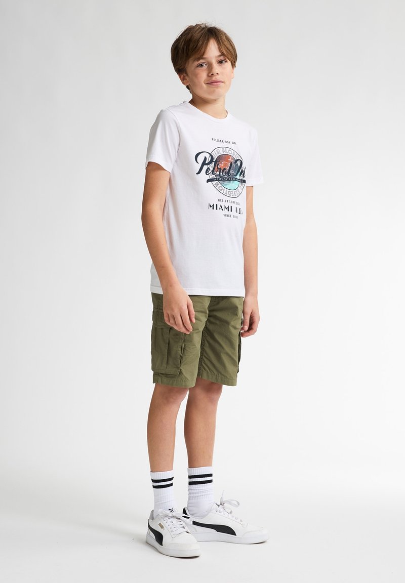 Camiseta blanca con un estampado gráfico en azul y naranja, combinada con pantalones cortos de cargo caqui, zapatillas blancas con detalles en negro y calcetines de rayas.