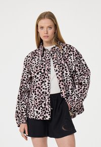 Leopardprint jas in roze en zwart, gemaakt van lichtgewicht stof. Voorzien van een knopenfront, twee voorzakken en elastische manchetten. Inclusief zwarte shorts.