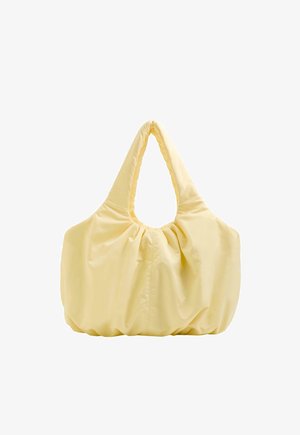 Puha sárga, túlméretezett válltáska széles, párnázott fogantyúkkal és összegyűrt anyag részletekkel az oldalakon és alul.