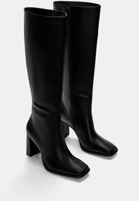 Schwarze kniehohe Lederstiefel mit quadrater Zehenform und klobigem Blockabsatz; ausgestattet mit einem seitlichen Reißverschluss und glatter Oberfläche.