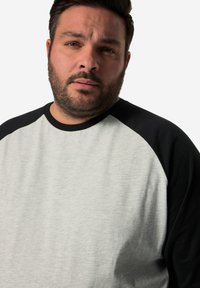 Grauer und schwarzer Raglan-Sweatshirt mit Rundhalsausschnitt, aus weichem Material und mit kontrastierenden Ärmeln. Keine sichtbaren Muster oder Hardware.