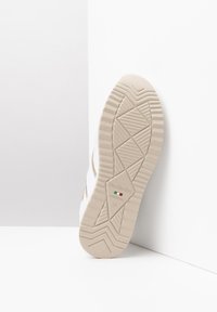 Białe sneakersy z teksturowaną gumową podeszwą, zdobione geometrycznym wzorem i złotymi akcentami. Oznaczone napisem "NeroGiardini" oraz "Made in Italy."