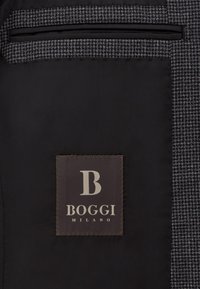 Tela negra con un patrón texturizado en gris; presenta una etiqueta marrón con "BOGGI MILANO" y un logotipo estilizado de la "B".