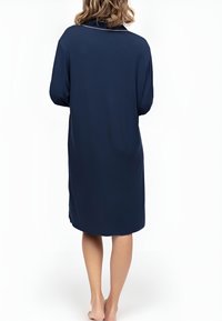 Robe de détente bleu marine avec une texture douce, des manches longues, un col et une coupe décontractée, présentant un ourlet arrière plus long et des fentes sur les côtés.