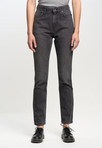 Jean en denim gris foncé avec taille haute, jambe droite, détails de couture subtils et design à cinq poches, associés à des chaussures noires à lacets.