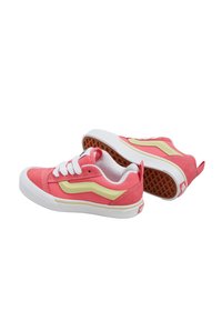 Baskets en suede rose avec des accents jaunes, des lacets blancs et une semelle en caoutchouc blanc. La semelle extérieure texturée en brun présente un motif en gaufre.