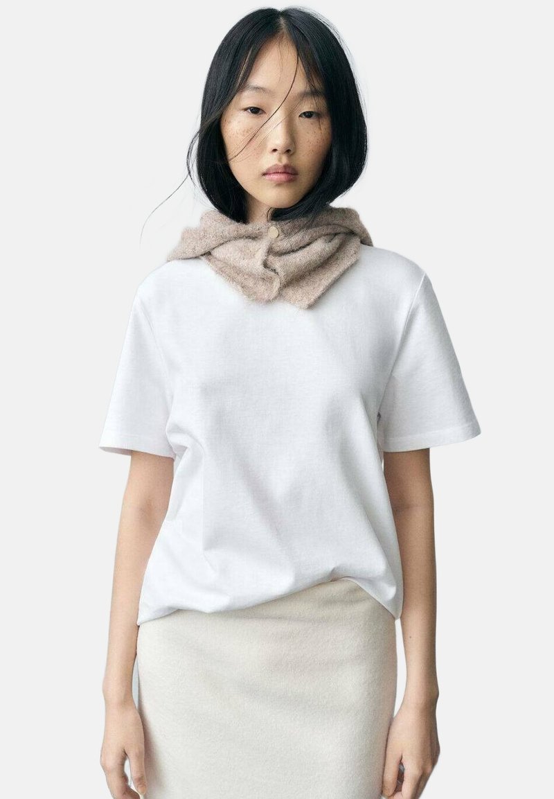 Vit bomull T-shirt med korta ärmar och en avslappnad passform, ihop med en ljusbeige scarf i mjukt stickat material runt halsen.
