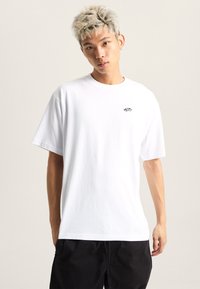White cotton t-shirt with short sleeves, crew neckline, and a small black logo on the left chest. Smooth texture, standard fit.
