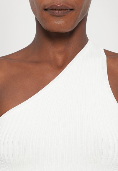 Asymmetrical white ribbed tank top featuring a one-shoulder design, showcasing a textured fabric and seamless construction.