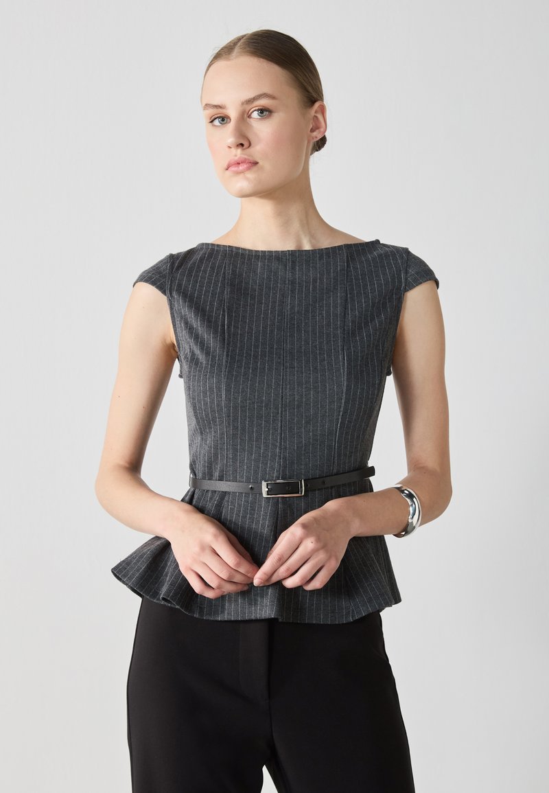 Šedý pruhovaný peplum top z textúrovanej látky, s krátkymi rukávmi a čiernym opaskom v páse. Nosený s čiernymi nohavicami.