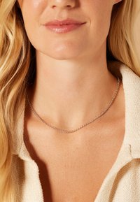 Collier en argent avec un design de chaîne délicate et fine. Porté autour du cou, mettant en valeur une texture lisse et un éclat subtil contre la peau.
