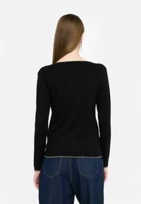 Musthave mustaline, millel on lai kaelus ja tekstuuriga ääris. Sobib kõrge vöökohaga teksadega, mis on vabalt langev.