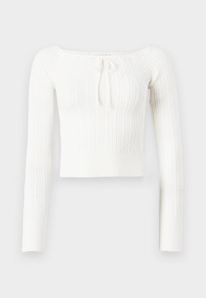 Maglione bianco a maniche lunghe, corto, con texture a coste e design a trecce. Presenta un collo a barca con un laccio regolabile.