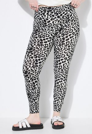 Leggings con stampa leopardata realizzati in un tessuto elasticizzato, con vita alta e vestibilità slim, abbinati a sandali a infradito bianchi e neri.