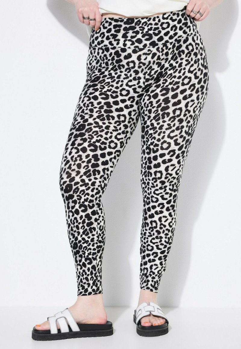 Leggings met luipaardprint, gemaakt van rekbare stof, met een hoge tailleband en slim fit, gecombineerd met zwart-witte instapsandalen.