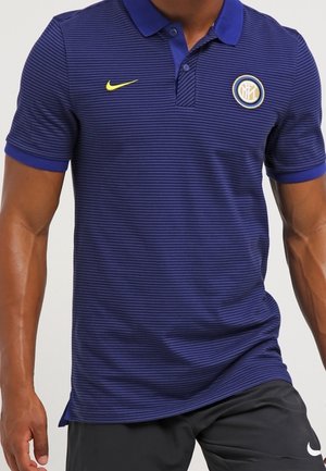 Hombre con una camiseta polo azul a rayas con el logo amarillo de Nike y el escudo del club de fútbol Inter de Milán en el pecho.