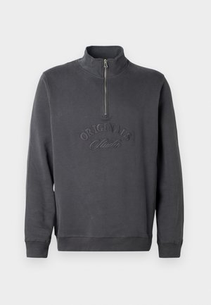Mörkgrå zip-neck sweatshirt i mjukt tyg, med broderad text "ORIGINALS Studio" på framsidan, långärmad och med ribbade muddar.