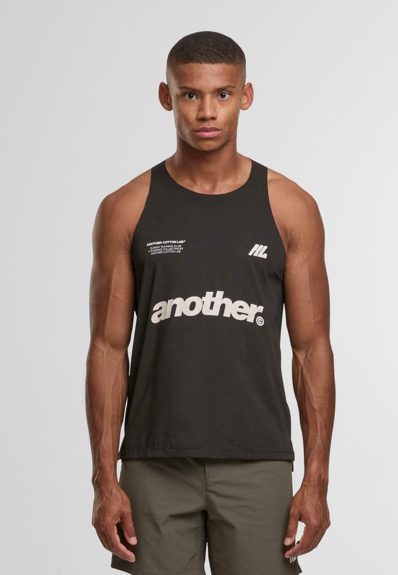 Top senza maniche nero caratterizzato da una texture liscia, scollatura rotonda e testo grafico bianco con la dicitura "another". Elementi distintivi includono un piccolo logo a sinistra.