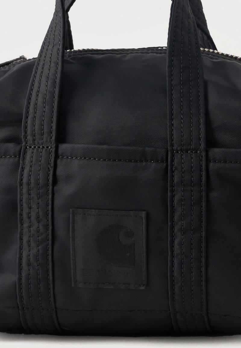 Borsa tote nera Carhartt con manici doppiamente cuciti e patch con logo sulla tasca frontale, mostrata su sfondo semplice.