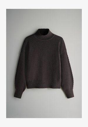 Megztinis tamsiai pilkas, su aukštu kaklu ir pūsto stiliaus rankovėmis, pasižymintis tekstūruota medžiaga ir pynimo detalėmis palei rankoves.