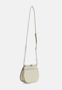 Specialdesignad axelväska i krämfärg med krokodiltextur, med en böjd form, silverkedja och tryckknapps-lås. Har två fack.