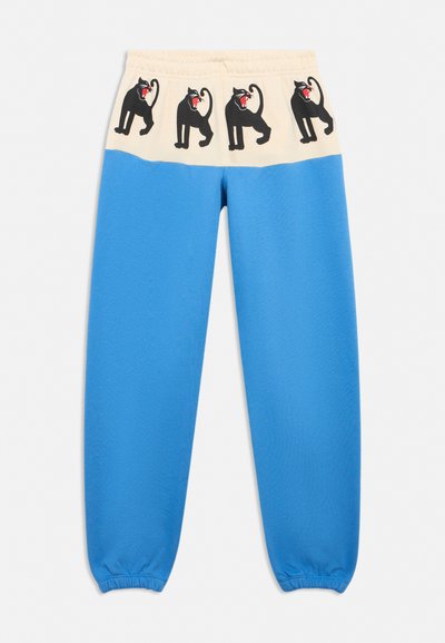 Blue sweatpants with a cream waistband featuring four black snarling panther designs in a row.
