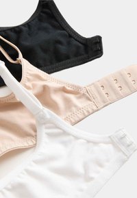 Drie beha's in zwart, nude en wit. Gemaakt van zachte stof, met verstelbare banden, haak-en-oogsluitingen en een gladde textuur.