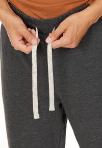 Grå sweatpants med dragsko i midjan, med vita och svarta prickiga dragskor. Slät tygtextur, med en avslappnad passform.