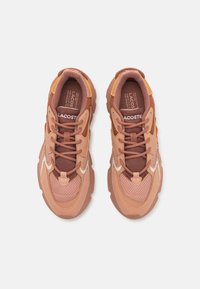 Lacoste tenisice u nijansama ružičaste i smeđe, od mrežaste i antilop kože, s obloženim jezikom i gumenim potplatom s žutim detaljima.