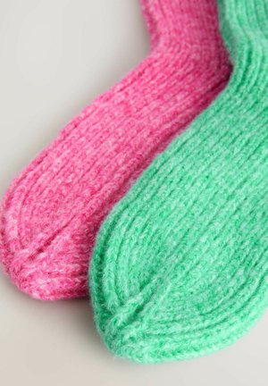 Chaussettes tricotées dans des teintes de rose et de vert, avec un motif texturé en côtes. Chaque chaussette présente un orteil arrondi et un matériau doux et duveteux.