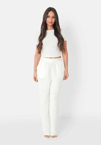 Hvid ribbet crop top parret med matchende højtaljede bukser. Har en afslappet pasform og sidelommer, med en glat tekstureret overflade.