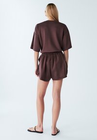 Brown cotton blend loungewear set featuring a relaxed fit T-shirt and shorts, with an elastic waistband and side pockets.