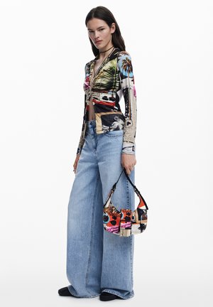 Maglietta aderente a maniche lunghe con una stampa grafica multicolore. Jeans in denim azzurro chiaro a gamba larga, con una piccola borsa a tracolla in patchwork.