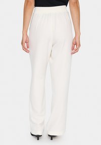 Witte wijde broeken met een gladde textuur en een elastische tailleband, met een subtiele draping en achterzakken, gedragen met een zwarte top.