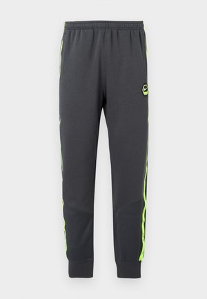 Pantaloni sportivi grigi con strisce laterali in giallo neon a contrasto e una toppa con logo nero. Presentano una cintura elastica e polsini affusolati.