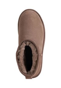 Brązowy zamszowy botek za kostkę z miękką podszewką z imitacji futra i zaokrąglonym noskiem. Botek ma przyszywaną podeszwę oraz małą pętelkę z tyłu.