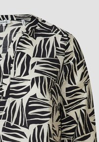 Zwart-witte blouse met patroon, gemaakt van een lichte stof, met een losse pasvorm en een splitnekontwerp. Abstracte bladvormen zijn zichtbaar.