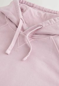 Sweat à capuche rose clair avec cordons de serrage réglables et détail de couture côtelée en forme de V près de l'encolure.