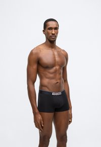 Fekete boxeralsó puha anyagból, kontrasztos logós derékpánttal. Az anyag sima, elasztikus nyúlással rendelkezik.