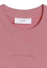 Ροζ φούτερ με λαιμόκοψη κόρωνα, ριμπ κολάρο, ετικέτα "Marc O'Polo DENIM" στο εσωτερικό και αχνό λογότυπο τυπωμένο στο στήθος.