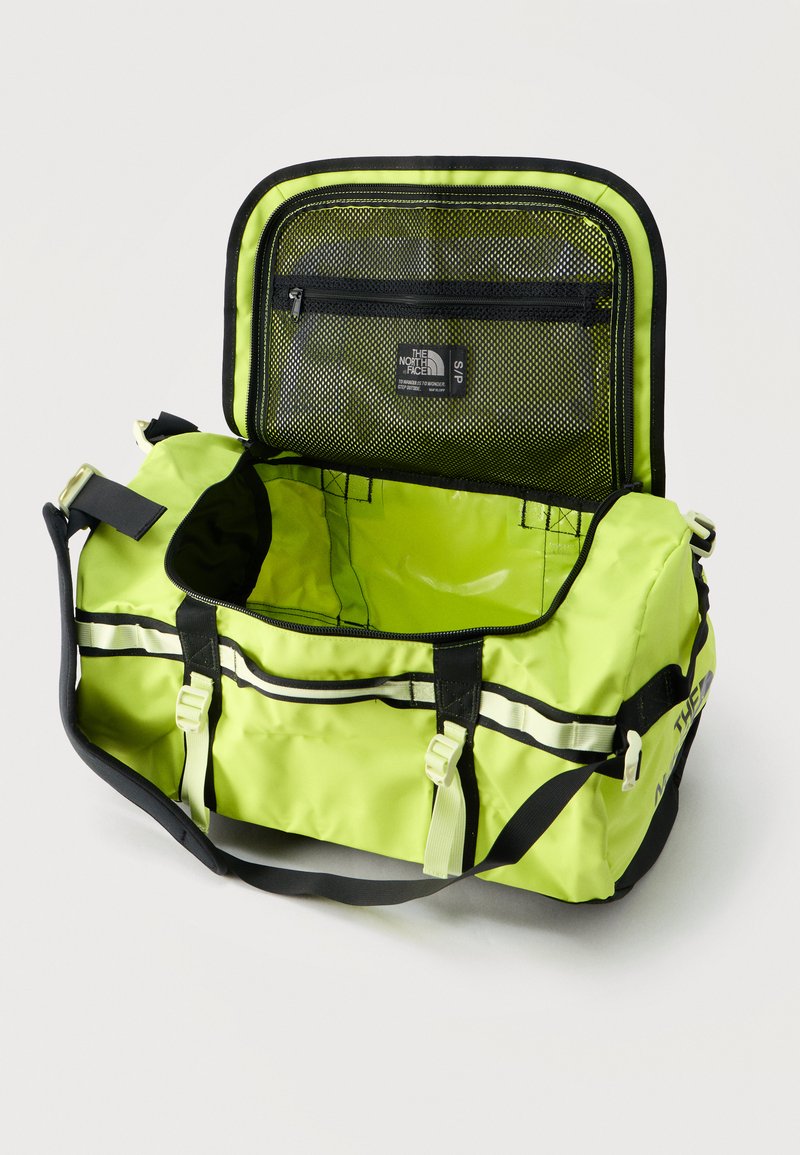Sac de voyage jaune-vert vif avec rabat supérieur ouvert montrant une poche zippée en mesh et un large compartiment principal.