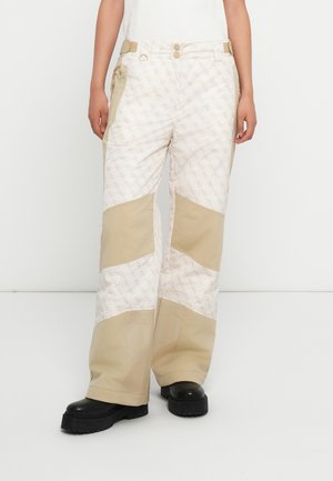 Beige en gebroken witte, met een patroon bedekte pantalon met wijde benen, voorzien van contrasterende effen panelen, ritszakken en een sluiting met twee knopen.